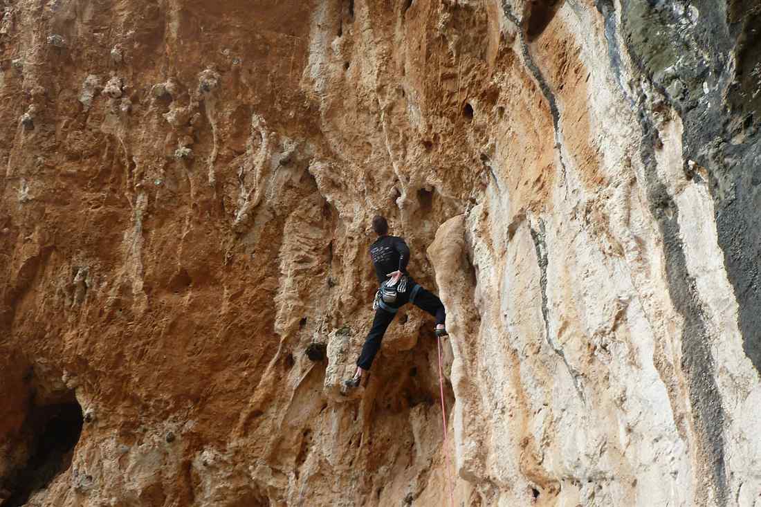 A climber on the orange limestone of a Kalymnos crag