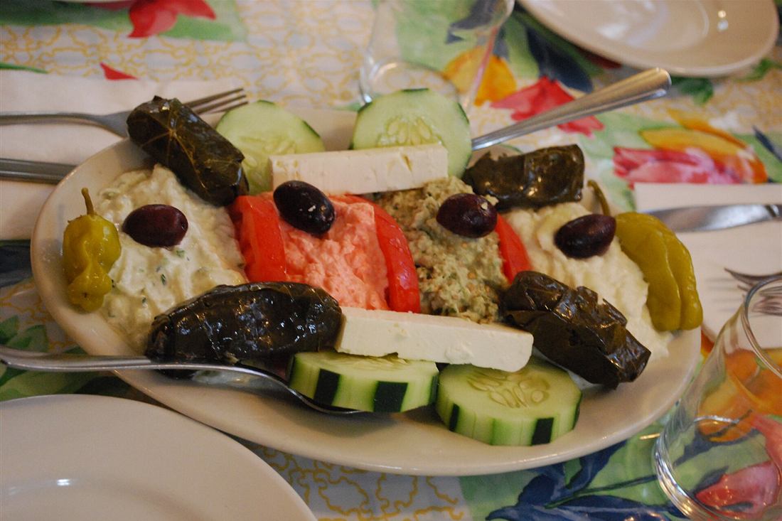 A Greek meze plate of dolmades, feta, tzatziki and taramosalata with olives and peppers, the tasting table on a Kavala food tour