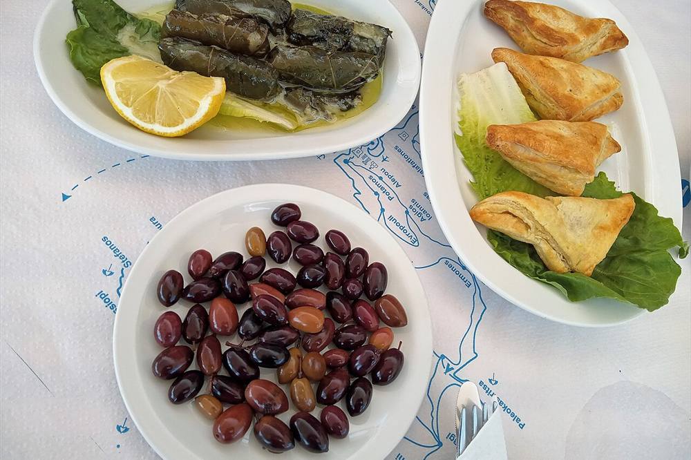 Dolmades, olives and cheese pies on a taverna table in Kefalonia