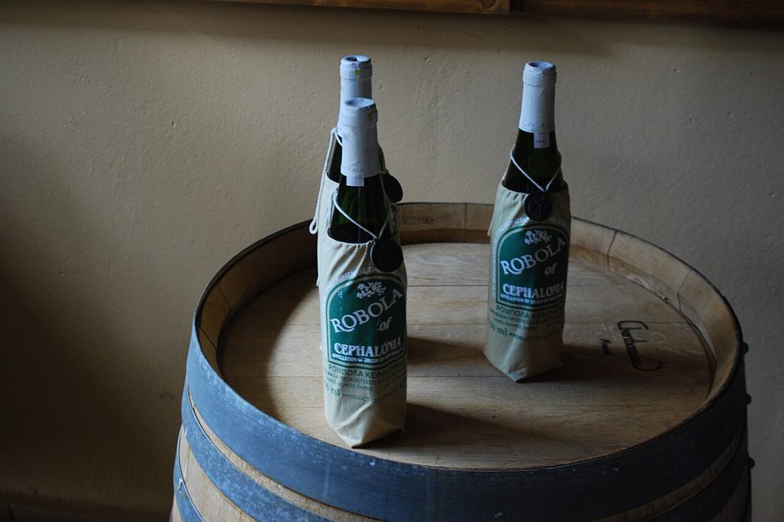 Bottles of Robola of Cephalonia standing on an oak barrel at a Kefalonia winery