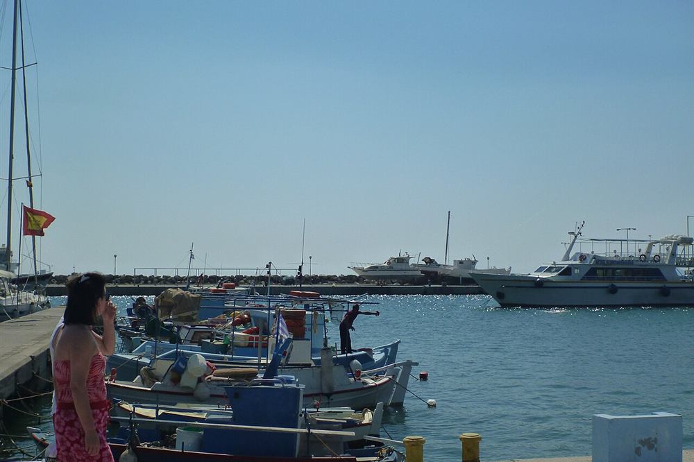Fishing boats moored along the quay at Kos harbour with a fisherman working on deck