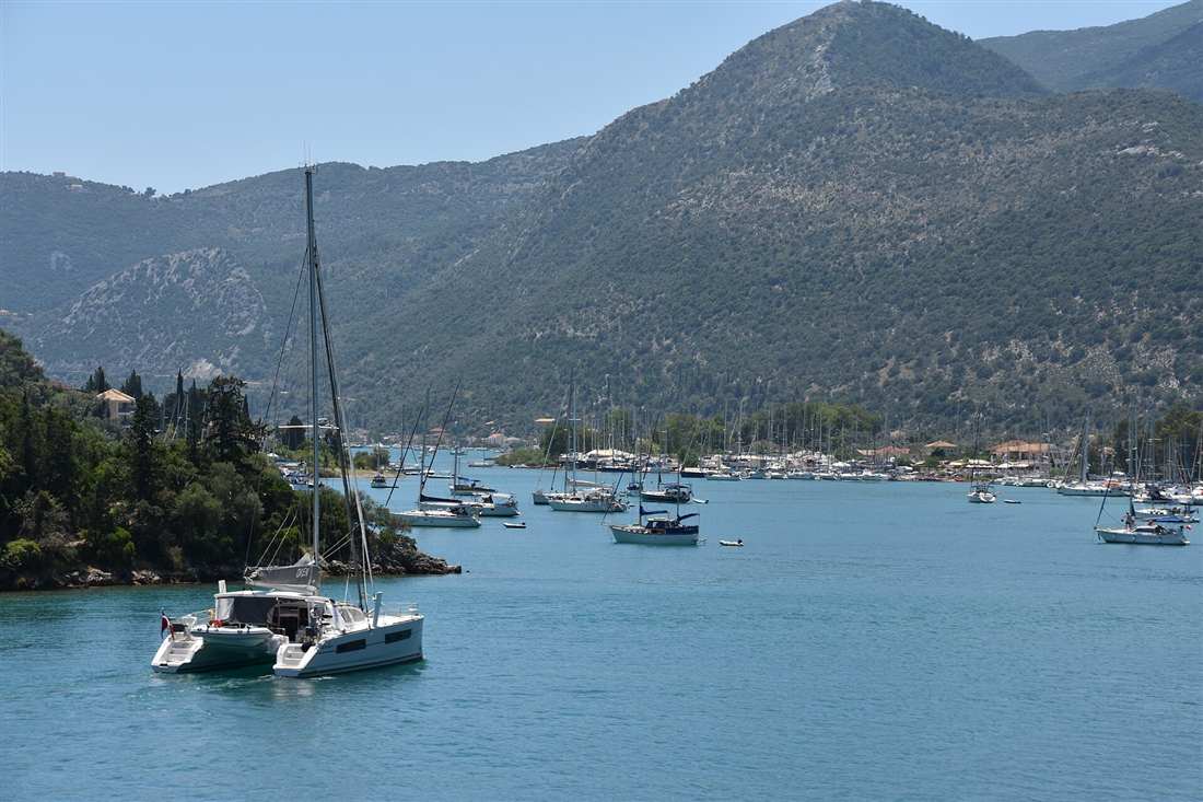 A catamaran leaving the yacht-filled bay at Nydri on a Lefkada yacht charter in the inner Ionian