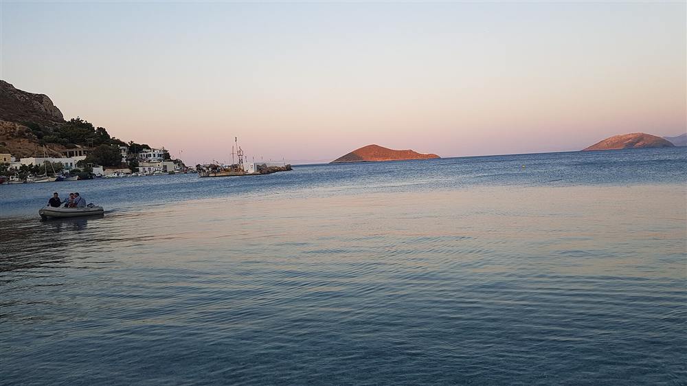 The sheltered bay of Pandeli on Leros at dusk with boats moored below the hill