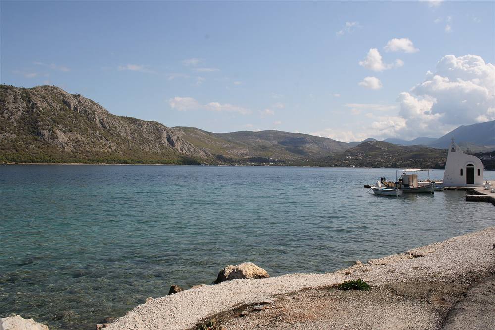 Lake Vouliagmeni of Perachora near Loutraki with its white chapel and moored boats