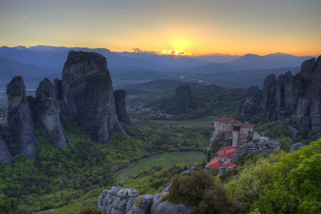 The Meteora rock pillars and a monastery at sunset above Kastraki