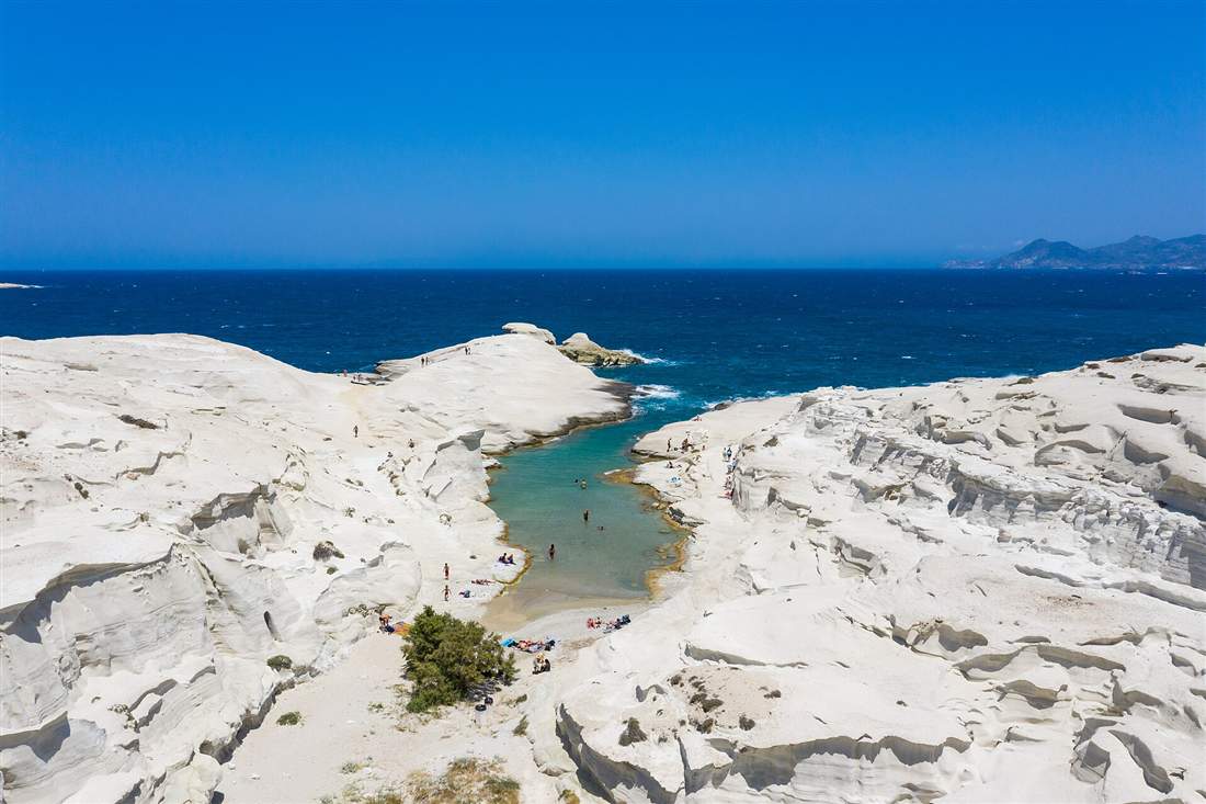 The white volcanic rock and turquoise inlet of Sarakiniko on Milos, the island reached by airport transfers from Milos Airport