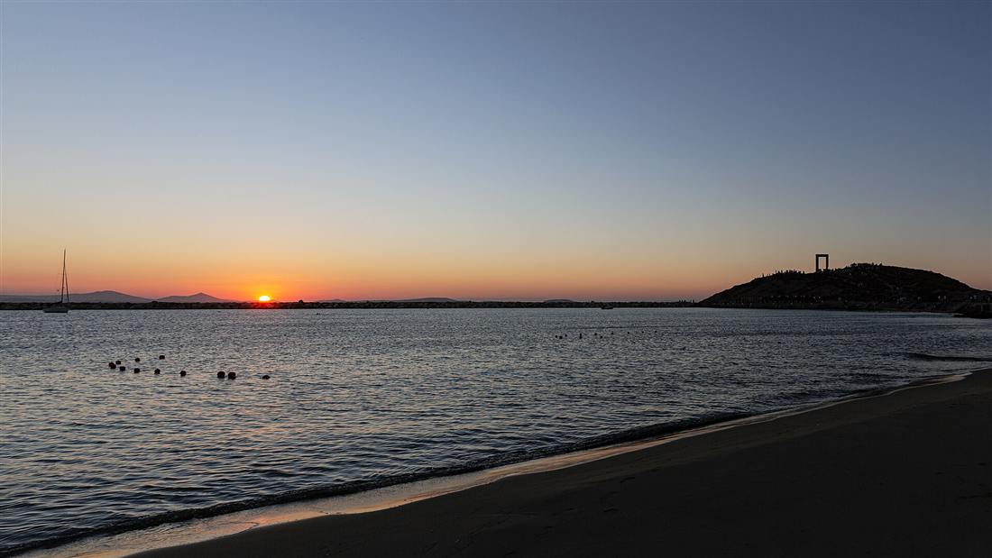 The Portara marble gateway on its islet by Naxos Town at sunset, a Naxos yacht charter landmark