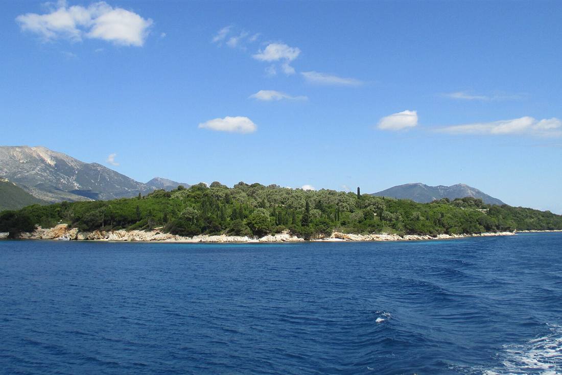 Nydri boat cruise running the Meganisi channel past a wooded islet