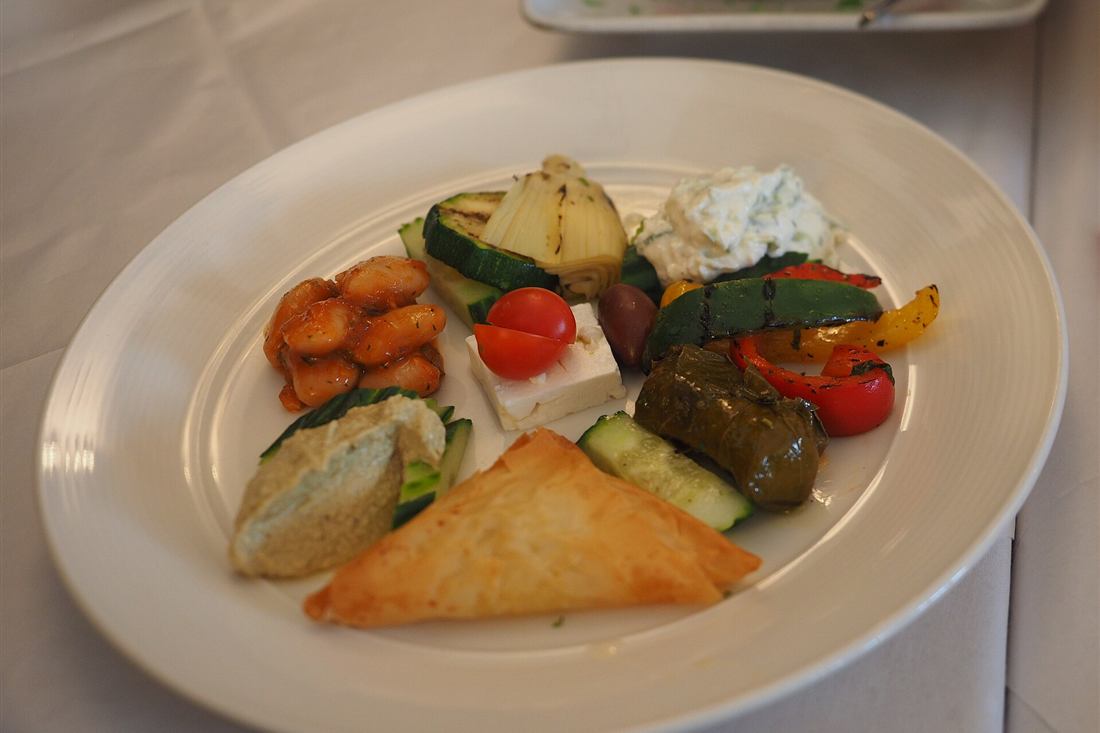 A Greek meze plate of dolmades, feta, tzatziki, cheese pie and grilled vegetables, the tasting plate on a Paros food tour