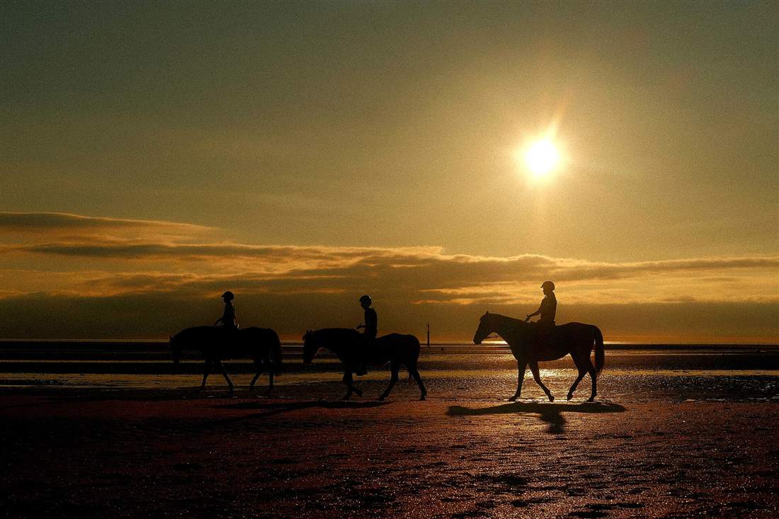 Riders on horseback along the shoreline at sunset, the evening Paros horse riding programme