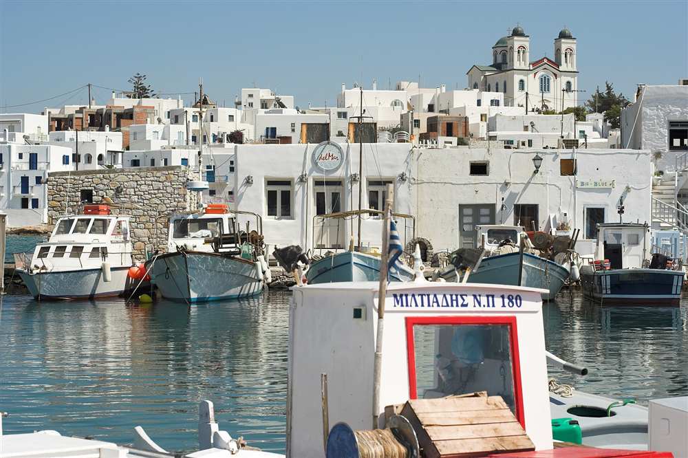 The fishing boats and whitewashed town of the harbour of Naoussa on Paros, Greece