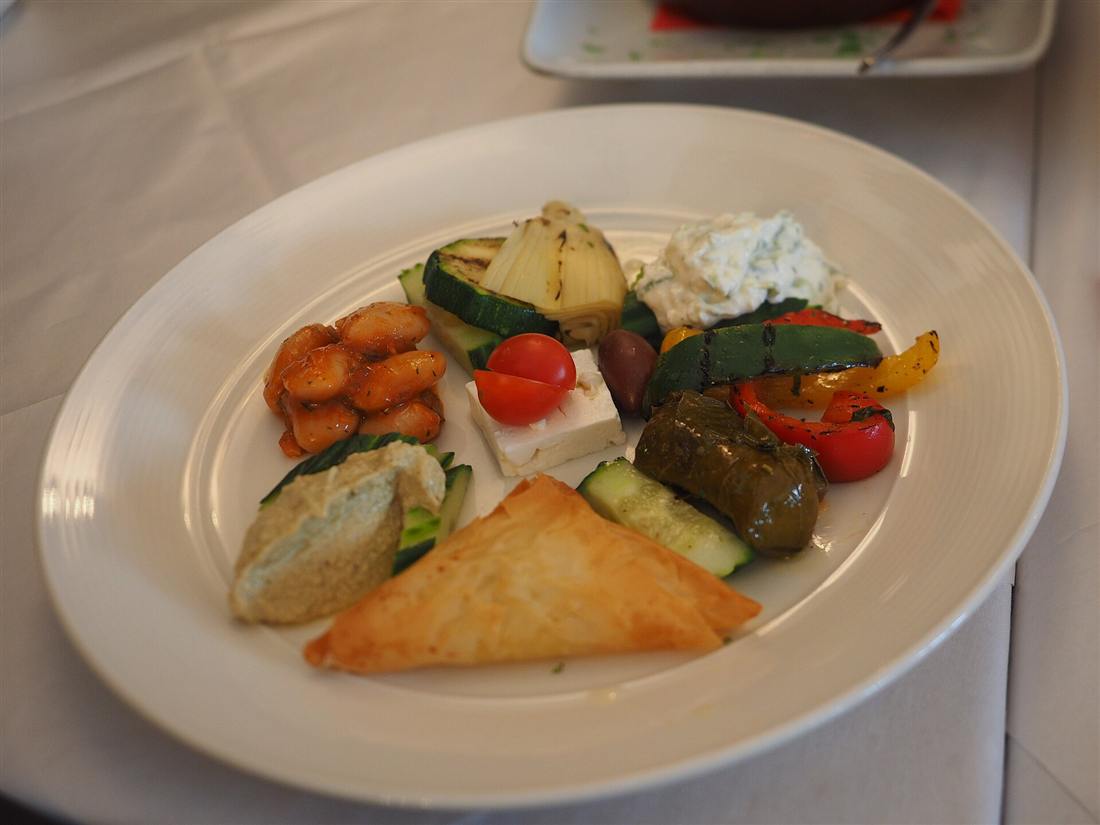 A plate of Greek appetizers with dolmades, feta, tzatziki, grilled vegetables and a filo pie, the kind of spread cooked on a Rhodes cooking class