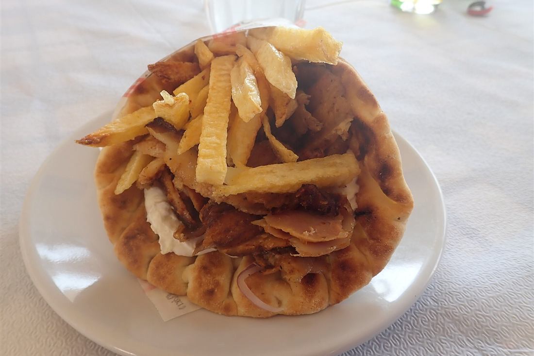 A pita gyros filled with meat and chips on a taverna plate, the street food tasted on a Rhodes food tour
