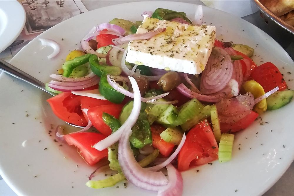 A Greek salad of tomato, cucumber, onion and a slab of feta with oregano and olive oil
