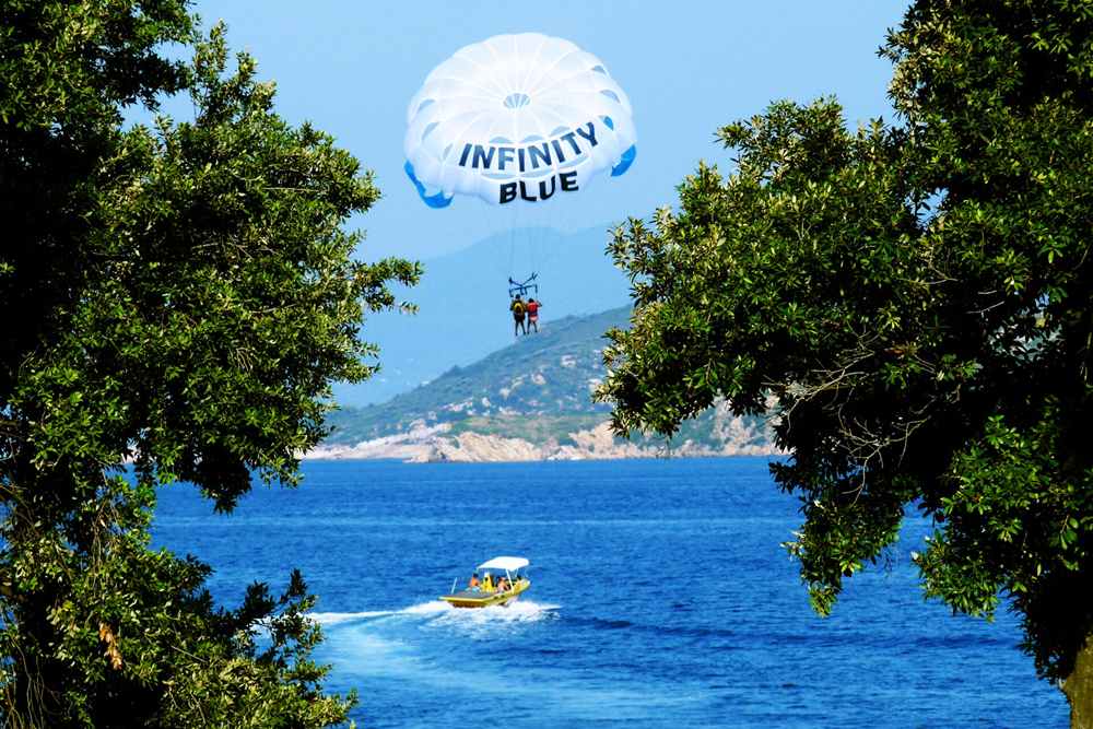 Tandem parasail canopy towed by a speedboat over a Greek bay, the flight format of Rhodes parasailing