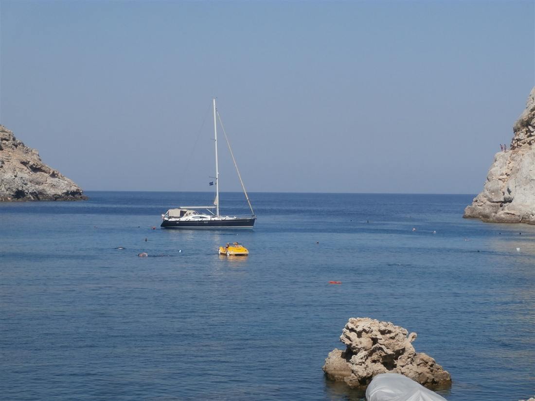 A sailing yacht anchored in the turquoise water of Anthony Quinn Bay on a Rhodes yacht charter