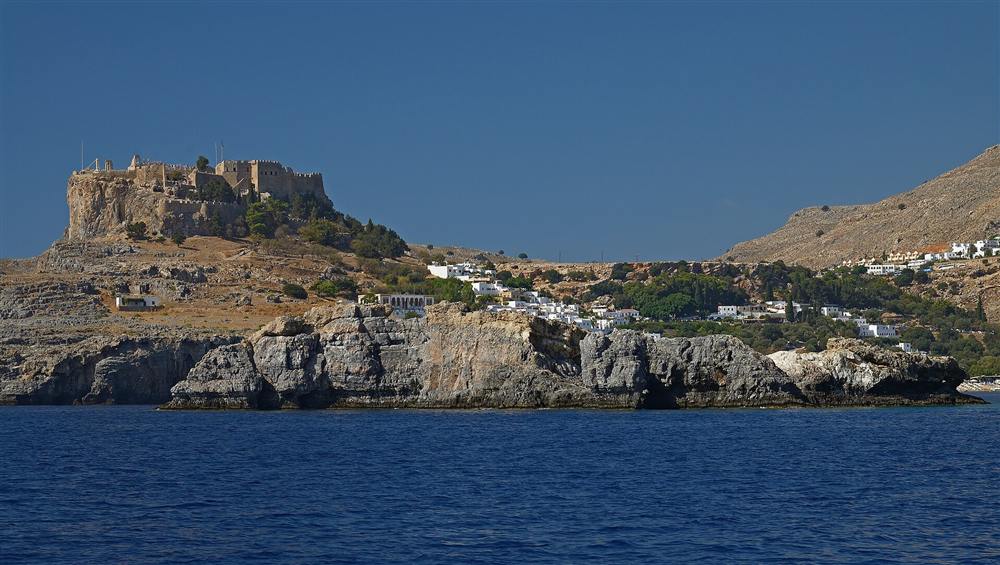 The clifftop acropolis and whitewashed town of Lindos on Rhodes seen from the sea