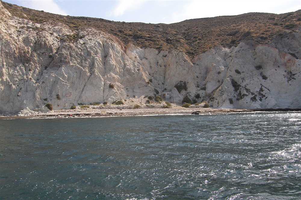 The white pumice cliffs and clear water of White Beach on the south coast of Santorini seen from the sea