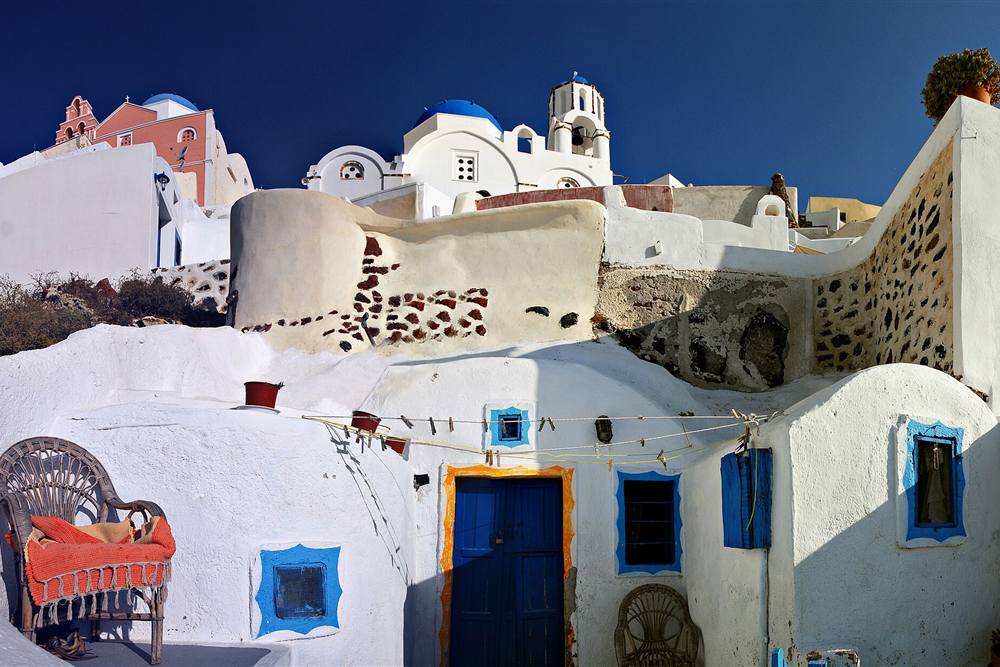 A whitewashed lane and blue-shuttered house in a caldera-rim village, the inland leg of the private route