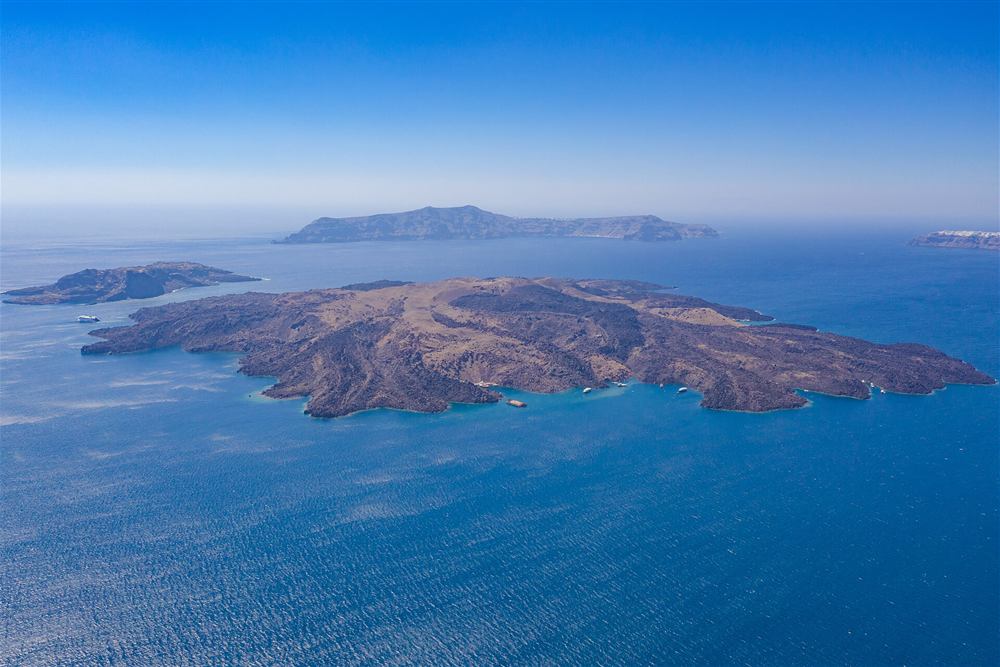 The Nea Kameni volcano island from the air with the caldera cliffs behind, a stop on the helicopter flight route