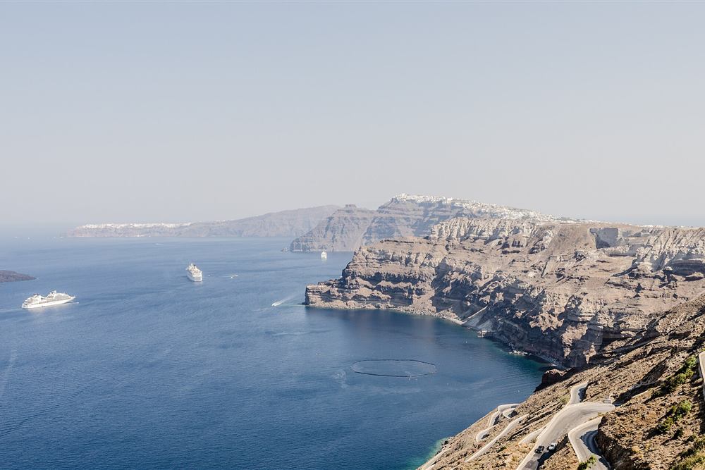 The caldera rim road above Fira with cruise ships anchored below, the drive and the cruise-port pickup on the private route