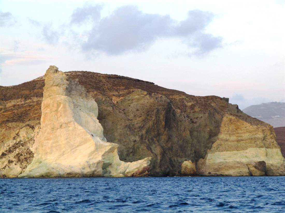 The layered volcanic cliff between White Beach and Red Beach seen from the water, the south coast a Santorini sea kayaking tour follows