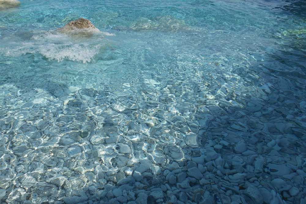 Clear water over the white marble pebbles at Lalaria beach on Skiathos