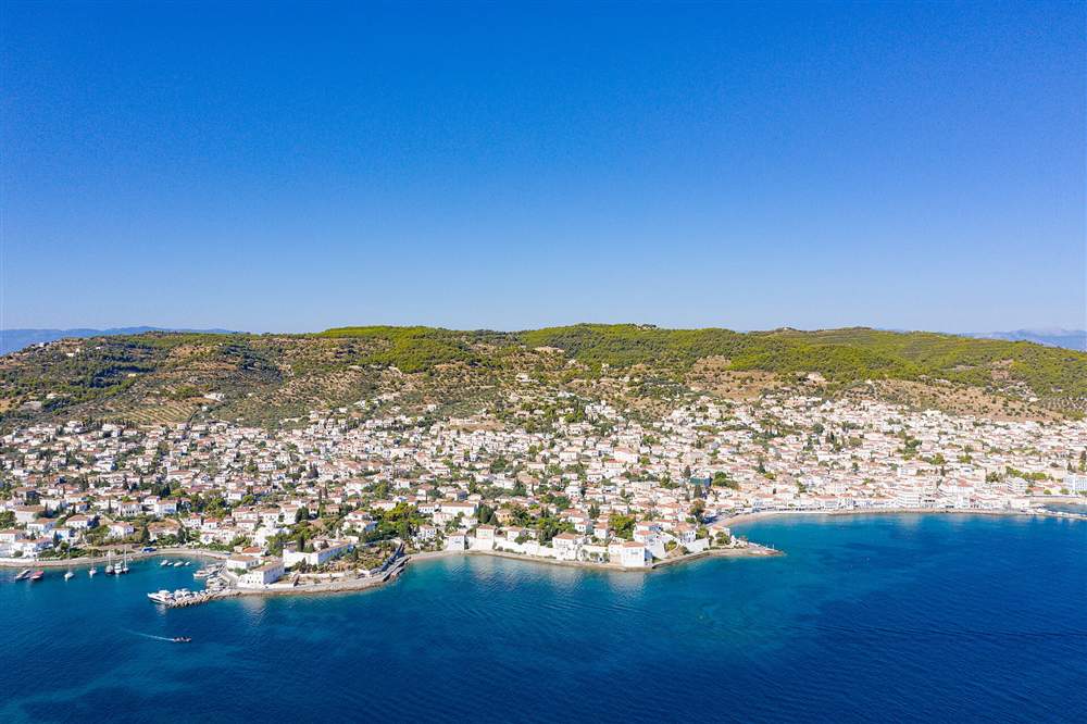 An aerial view of Spetses town spread along the pine-green coast of the Saronic island