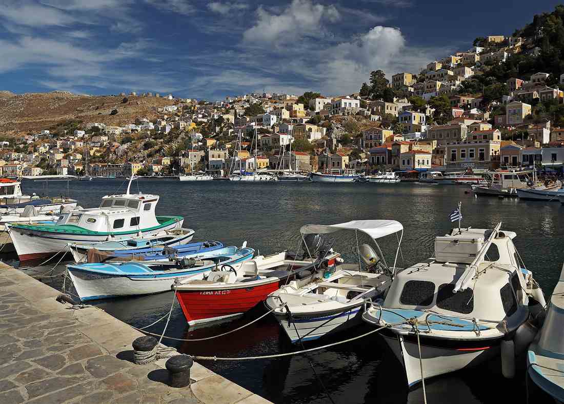 The Gialos harbour of Symi ringed by tiers of neoclassical mansions with yachts and boats moored, a base for a Symi yacht charter