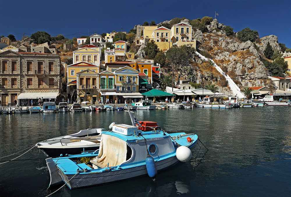 The colourful neoclassical houses and moored boats of the Gialos harbour on Symi in the Dodecanese