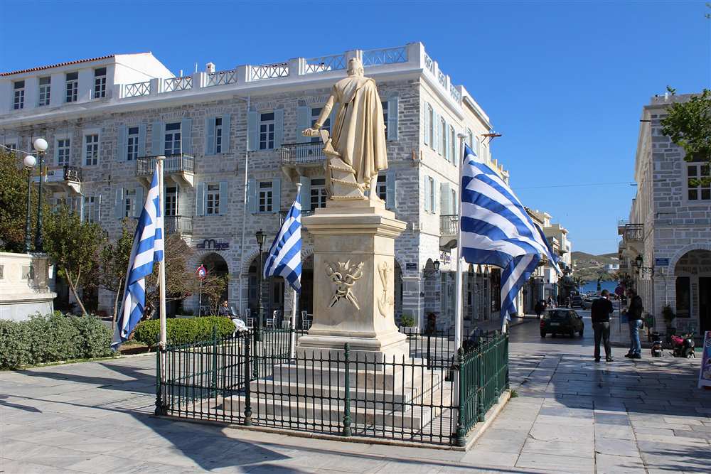 Walkers crossing Miaouli Square past the Miaoulis statue in Ermoupoli