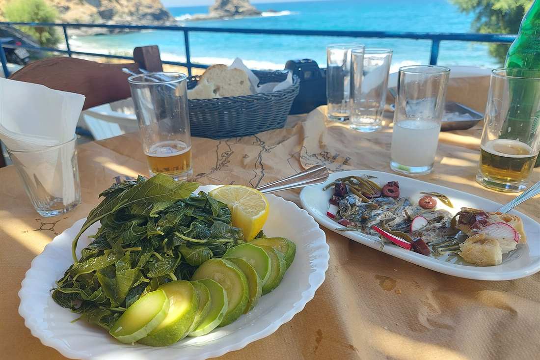 Thassos cooking class: Greek dishes of greens, fish and bread on a seaside taverna table in Greece