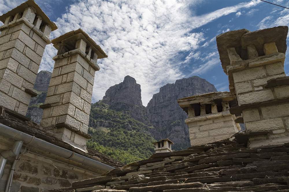 Stone roofs and chimneys of Mikro Papigo under the Astraka towers, Zagori