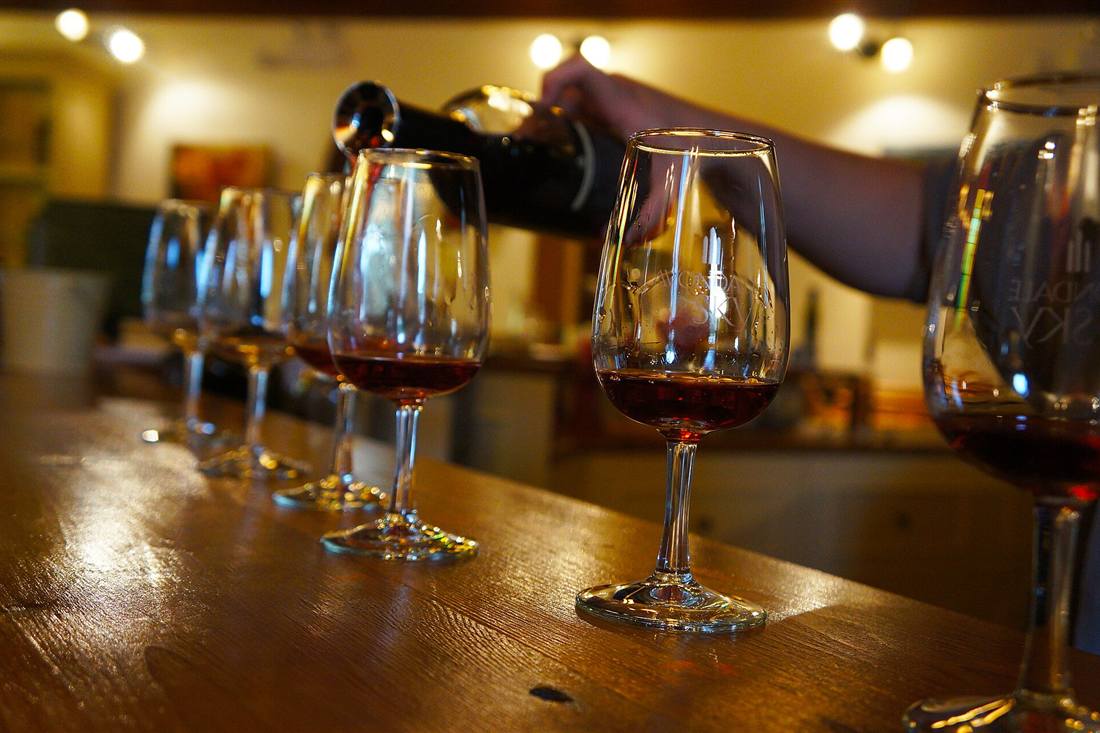 A row of tasting glasses being poured at a winery counter, the cellar tasting at the heart of a Zakynthos food tour