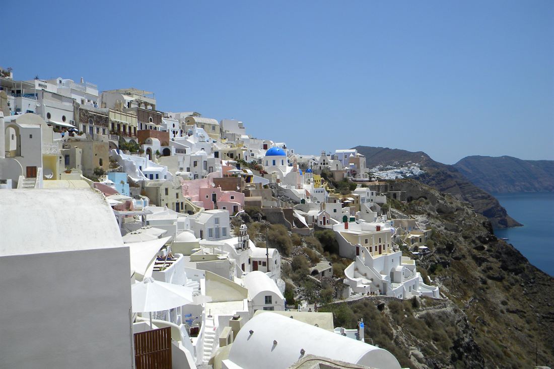 White houses with blue-domed churches stacked on a cliff above the Santorini caldera