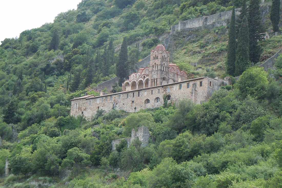 The Pantanassa monastery with its domed church and bell tower on the green hillside of Mystras, below the old walls.