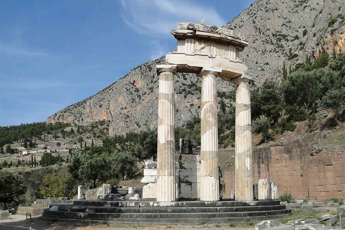 The Tholos of Athena Pronoia at Delphi, with three restored Doric columns on a round base below the cliffs of Mount Parnassus.