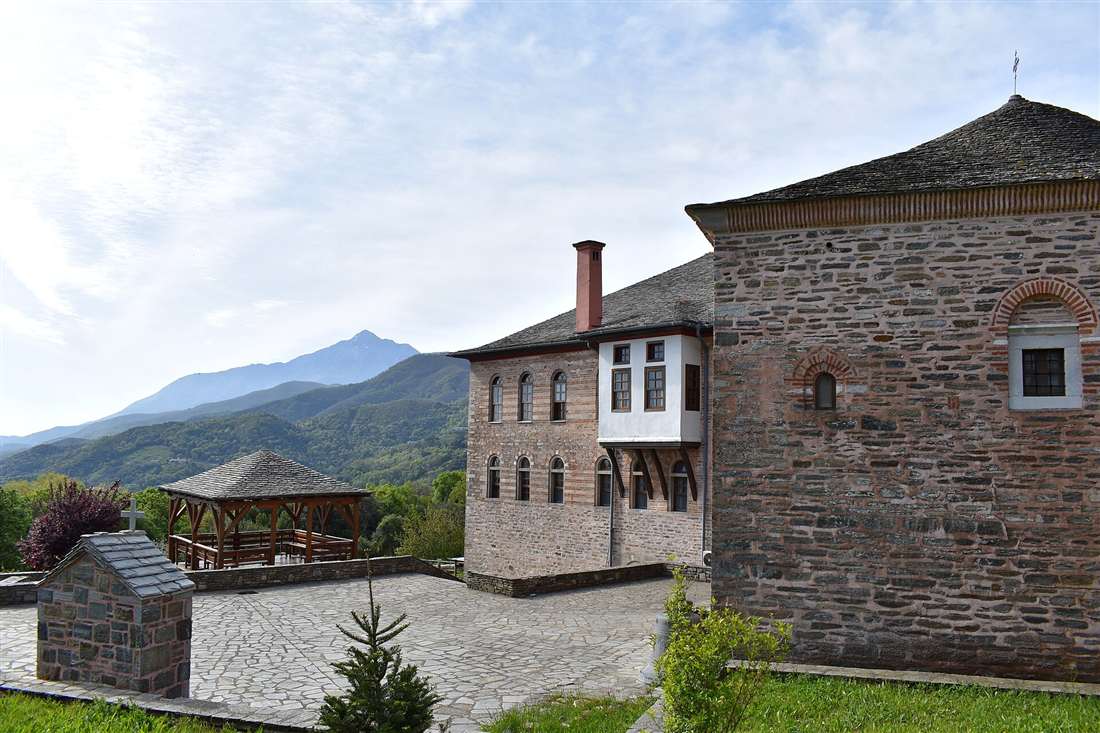 Stone buildings at Karyes on Mount Athos, with the peak of Athos rising behind green forested hills.