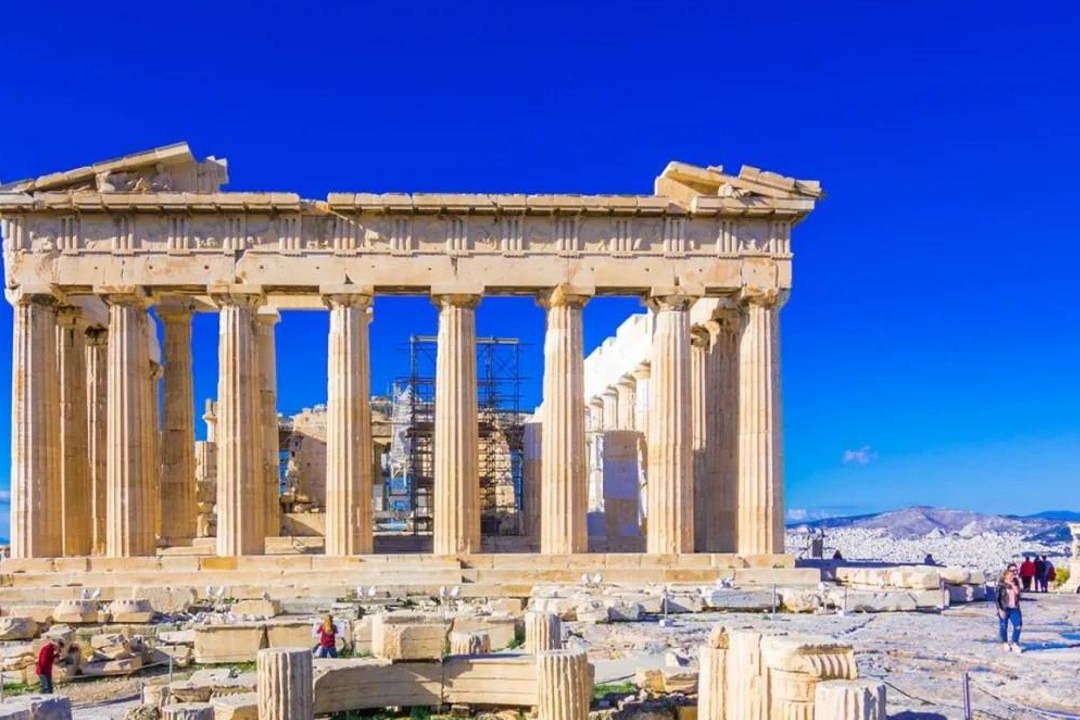 The Parthenon on the Acropolis of Athens under a deep blue sky, with fallen marble blocks in front.