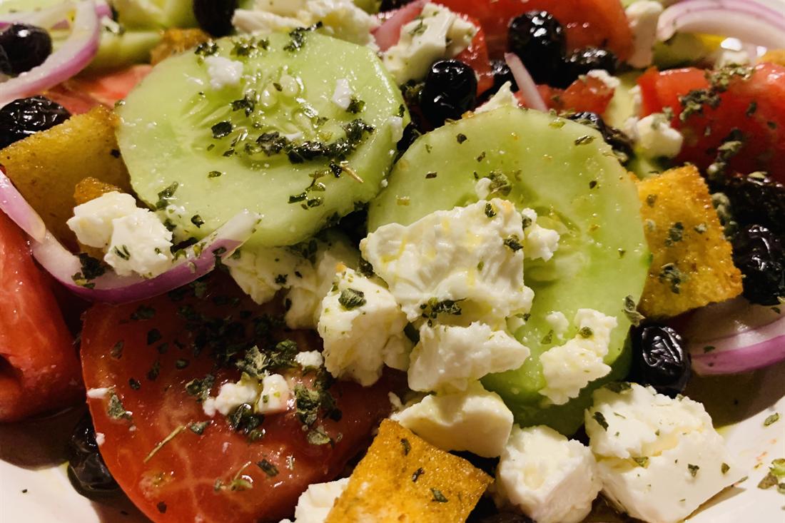 Greek salad with crumbled feta cheese, cucumber, tomato, black olives, red onion and croutons