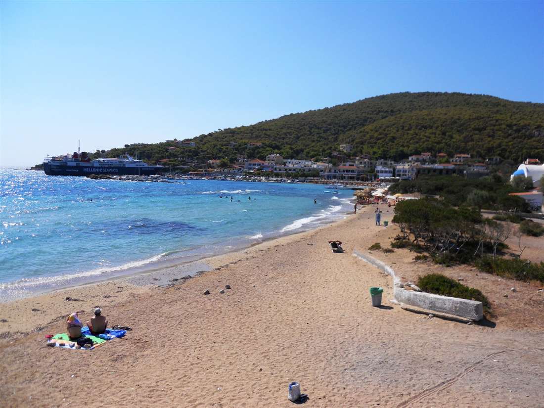 The bay of Skala on Agistri with turquoise water, a sandy beach and pine-covered hills, a stop on an Agistri boat trip.