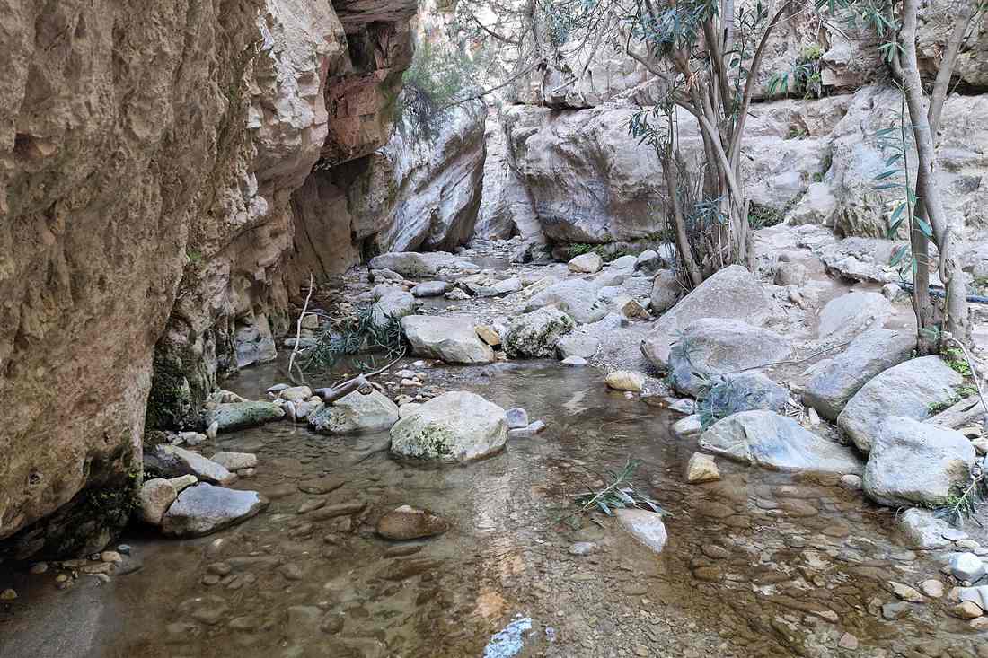 Shallow stream among boulders between limestone walls in Avakas Gorge