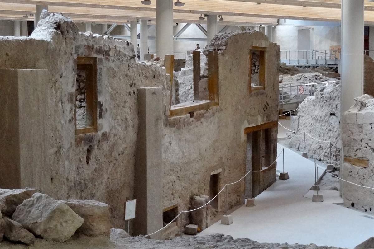 Akrotiri tickets lead visitors along the street past the multi-storey West House and its window frames under the protective roof.