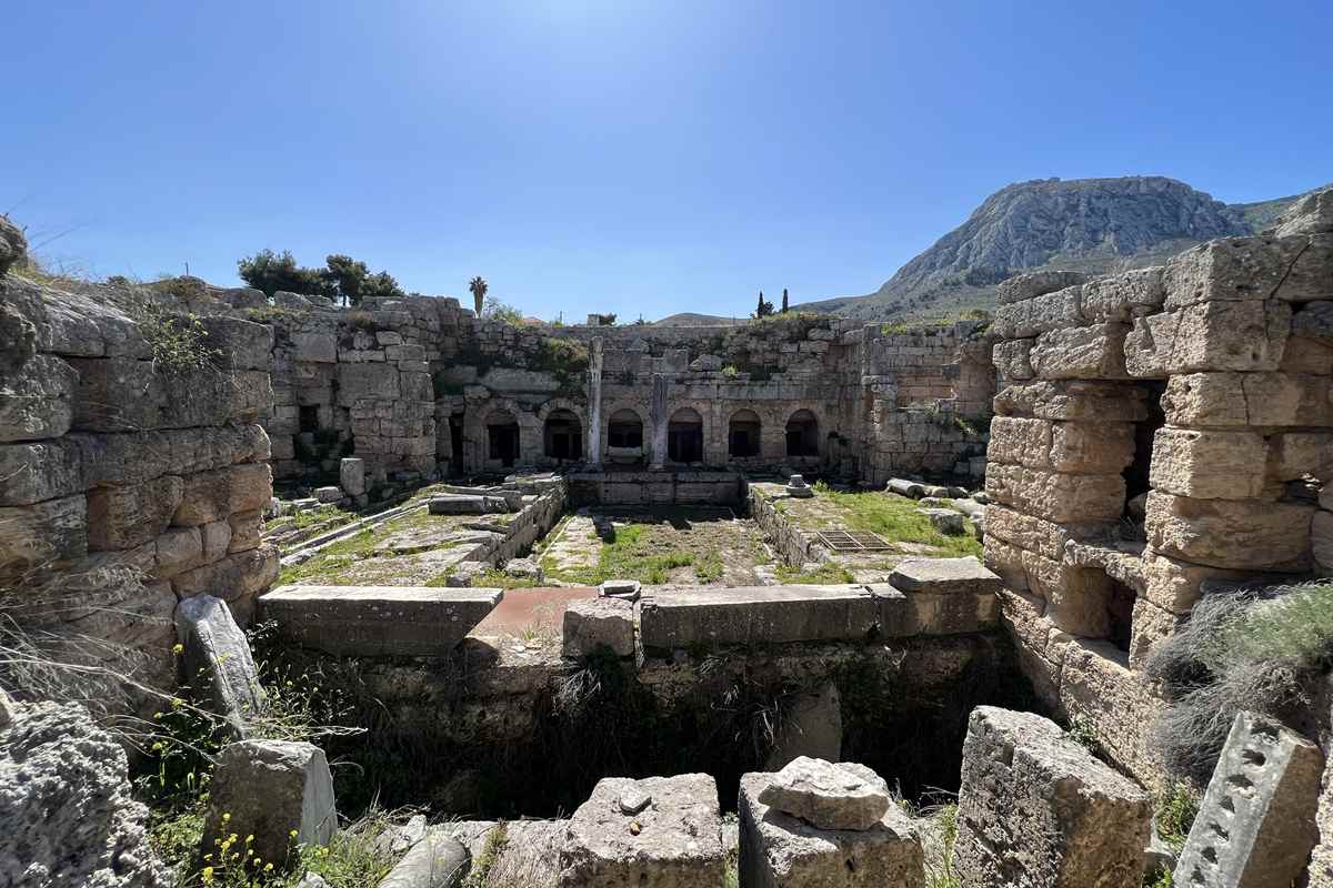 The arched chambers of the Peirene fountain, a stop on a self-guided Ancient Corinth tour, sit below the rock of Acrocorinth.