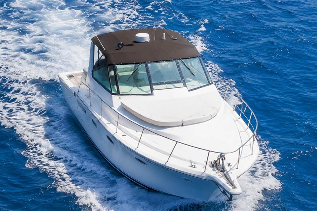 A white motor yacht speeds across deep blue sea, leaving a long white wake, on an Antiparos day trip from Naxos.