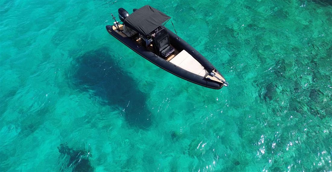 A motor boat floating over shallow turquoise water seen from above