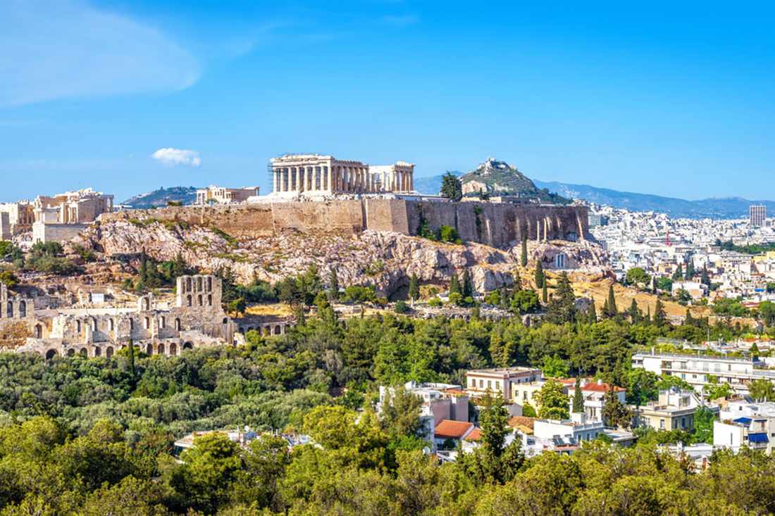 The Acropolis of Athens with the Parthenon on its rock above green trees and the city, a site an Athens city pass covers.