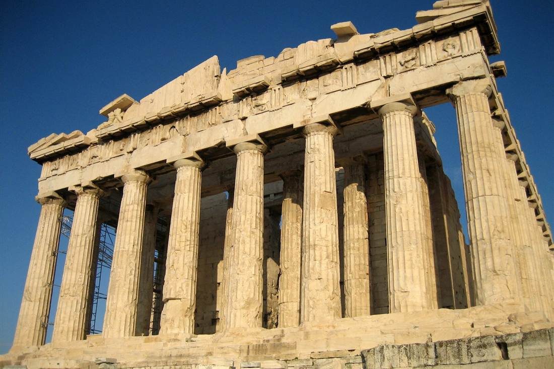 The west front of the Parthenon on the Acropolis of Athens, with its Doric marble columns and pediment in warm light under a deep blue sky.