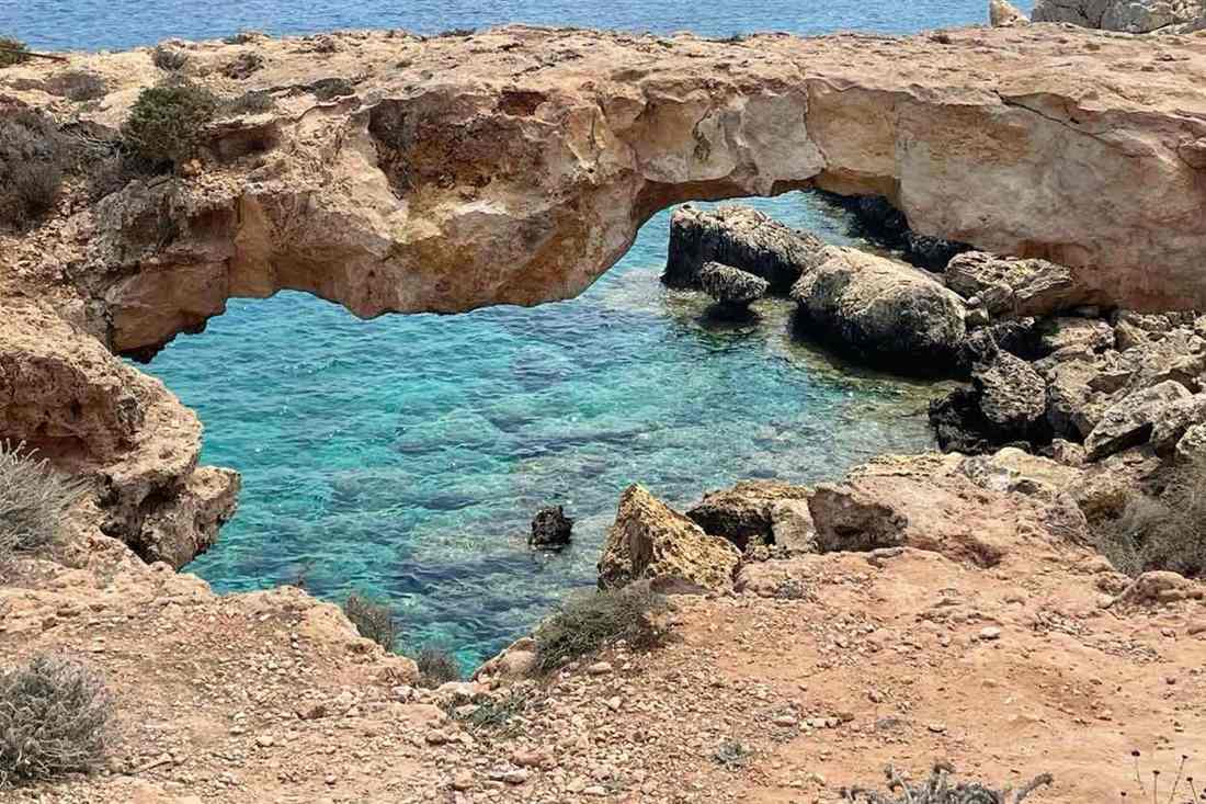 The natural rock arch of the Love Bridge over clear turquoise water at Cape Greco near Ayia Napa