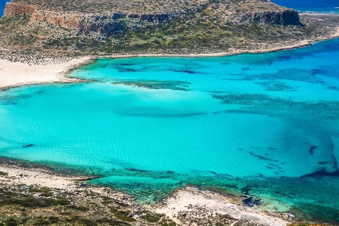 The shallow turquoise lagoon of Balos below a rocky headland, seen from above on a Balos day trip from Rethymno.